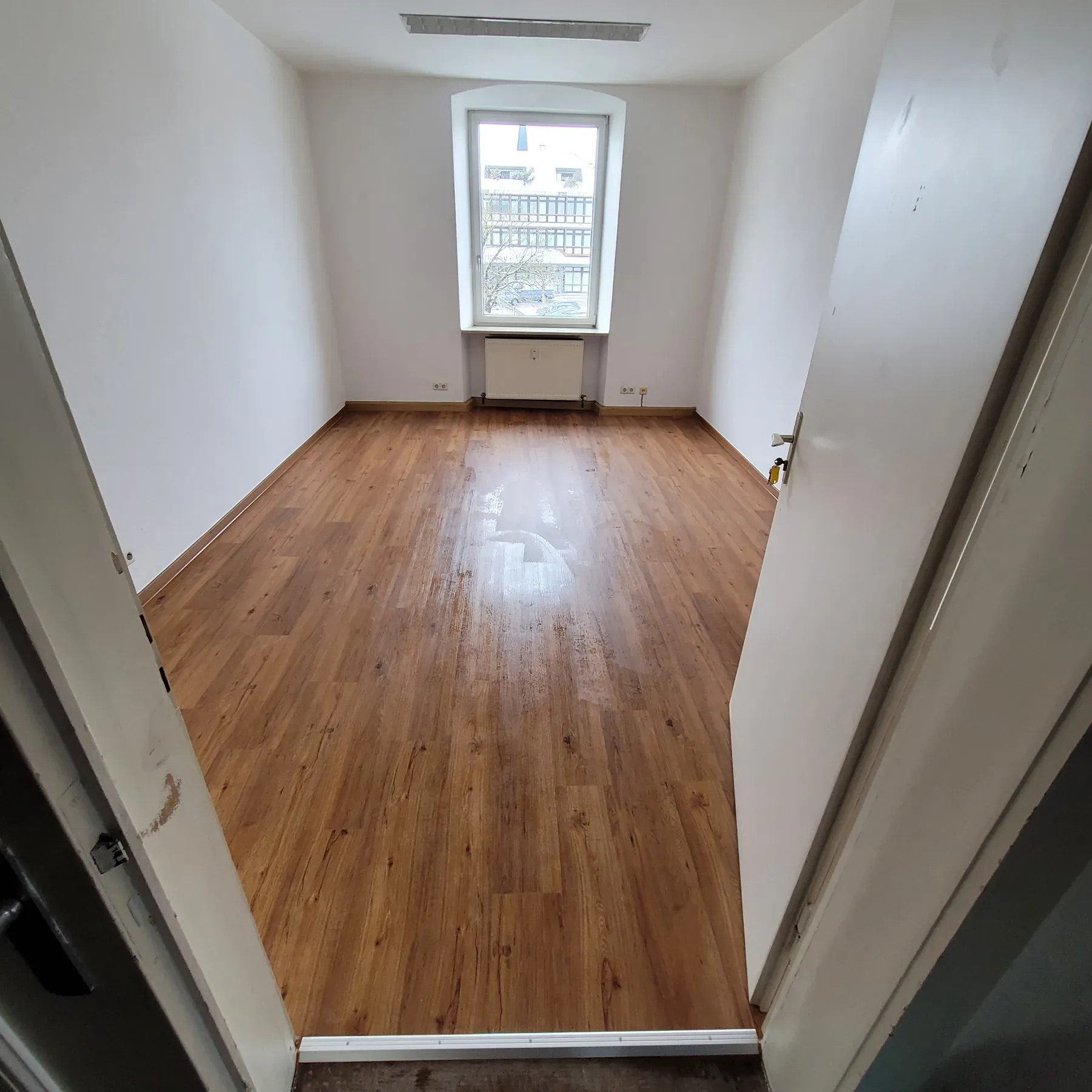 Renovierter Raum mit sauber verlegtem Holzboden und hellen Wandflaechen