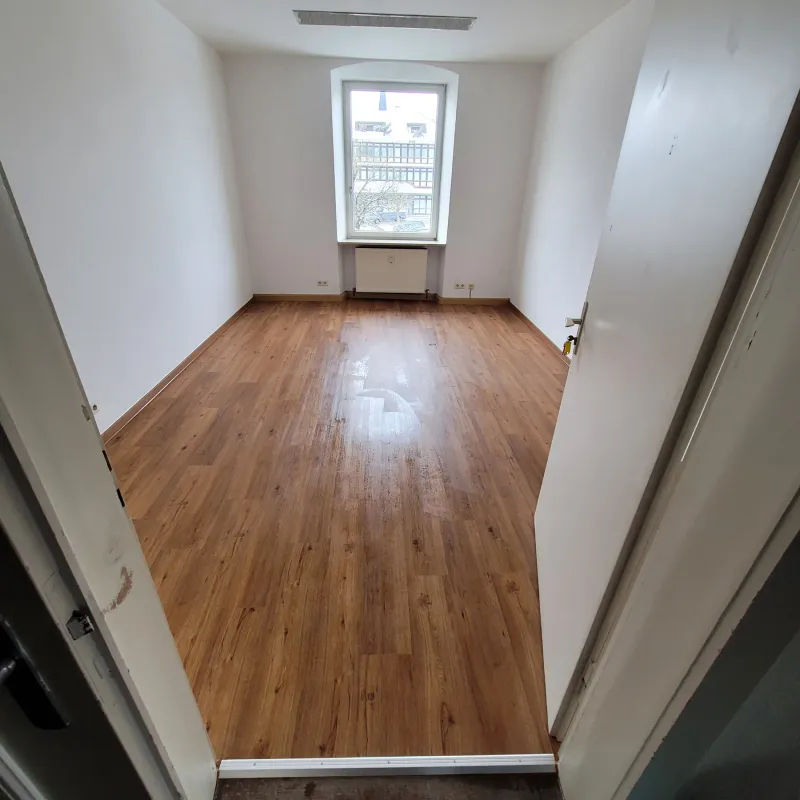 Renovierter Raum mit sauber verlegtem Holzboden und hellen Wandflaechen