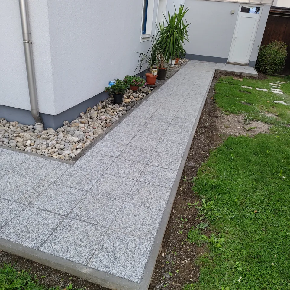 Neu verlegte Plattenfläche an einer Terrasse mit angrenzender Grünfläche